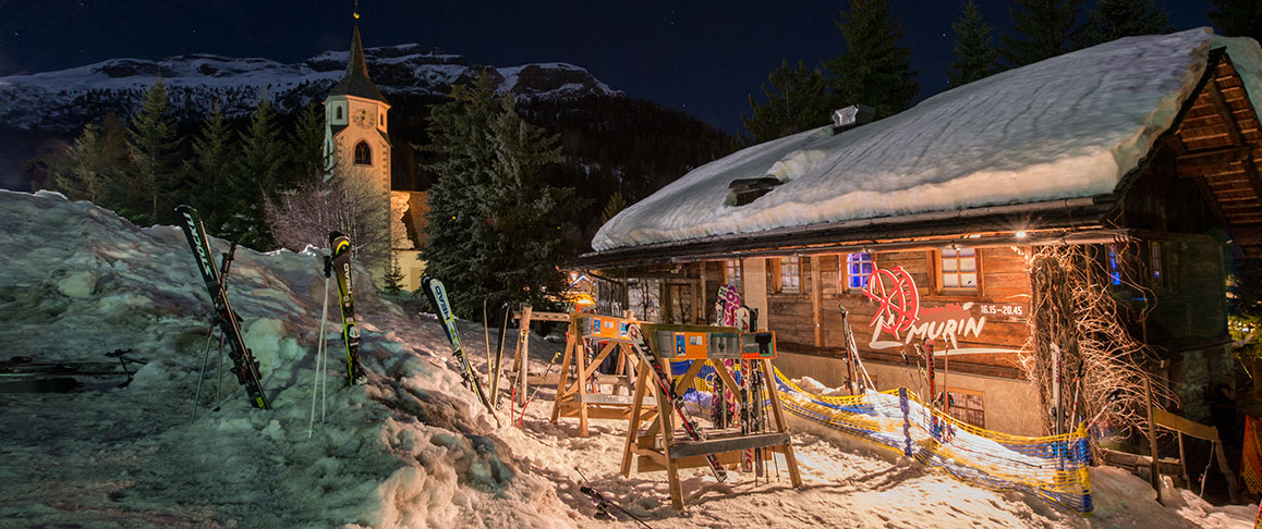 eine beleuchtete Hütte im Winter in Corvara