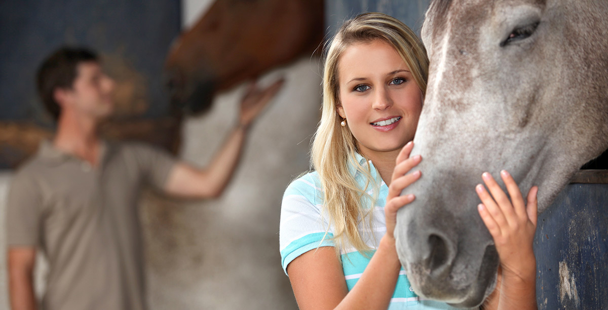 Blonde woman caresses the muzzle of a horse
