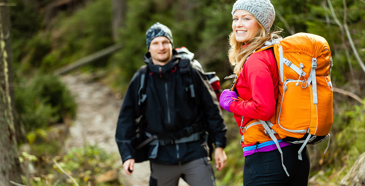 Man and woman with mountain clothing run through a path