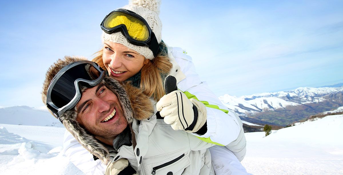Uomo e donna si divertono sulla neve vestiti con abiti da sci