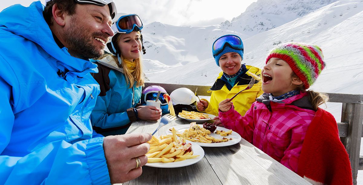 Mamma, papà e due figlie mangiano dopo una sciata sulla neve