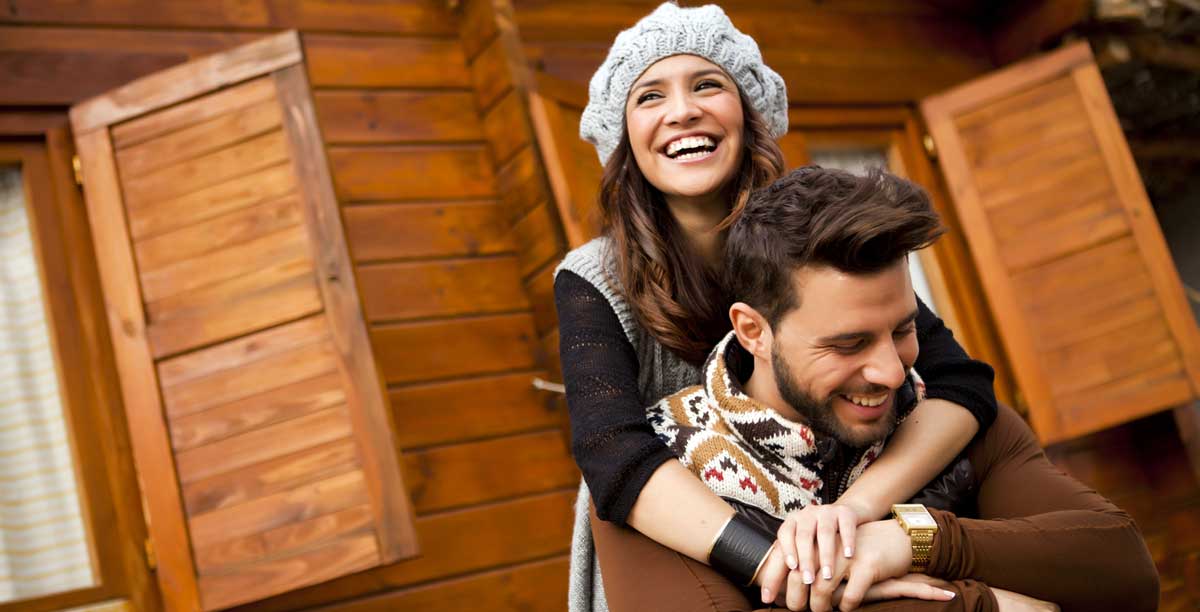 Una giovane coppia sorridente nei pressi di una baita