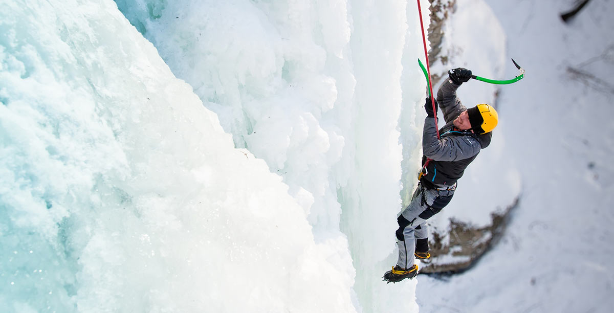 Un uomo sospeso con una corda su una parete di ghiaccio si arrampica