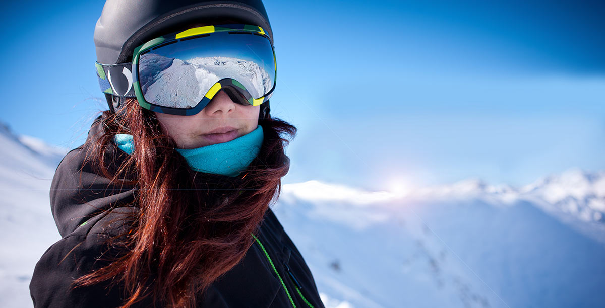 Close up of a woman with red hair, helmet and goggles ski