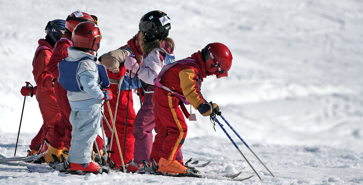 Children with helmet and breastplate try to ski