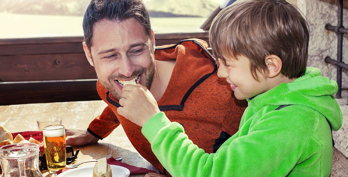 Child let his father taste a piece of his sweet 