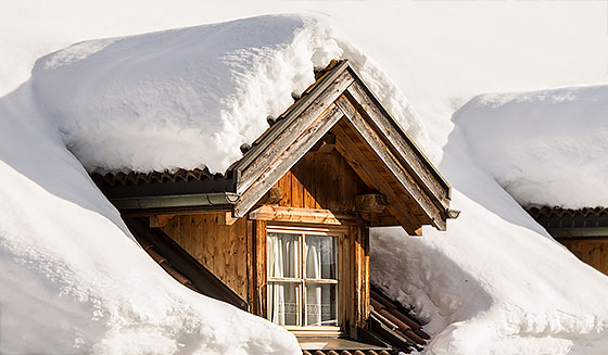 Detail eines Fensters einer verschneiten Hütte im Winter in Corvara