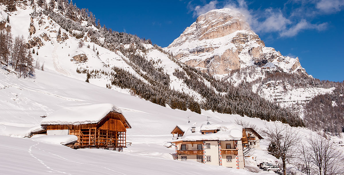 Eine Scheune aus Holz und ein mehrstöckiges Haus von schneebedeckten Bergen umgeben